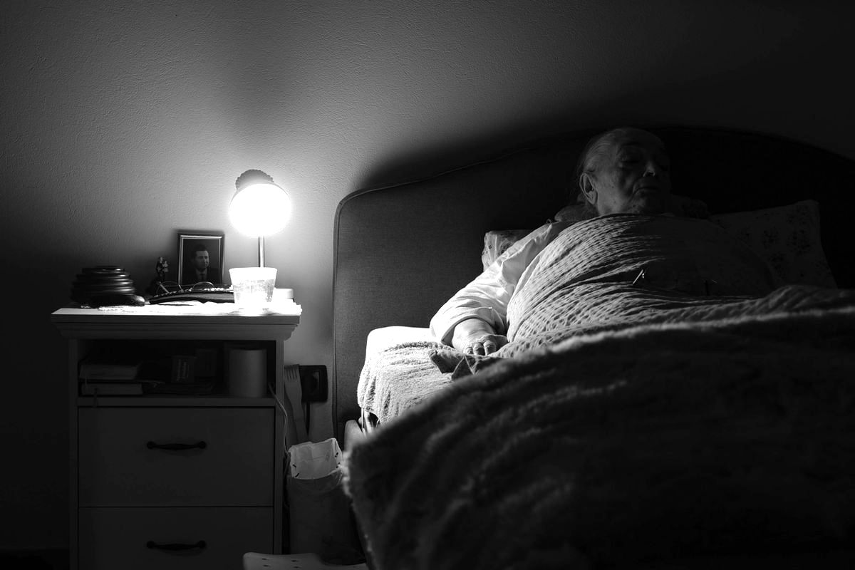 An older woman in bed at night, about to get up in the dark