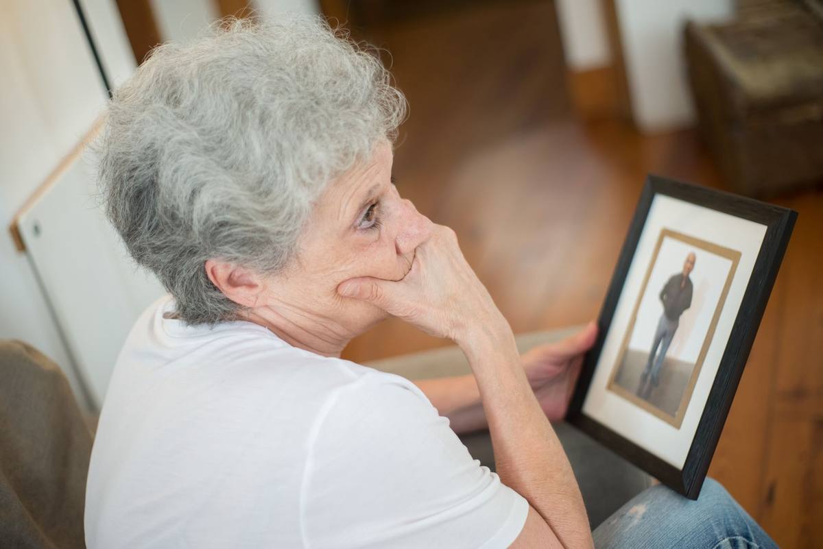 Elderly woman holding a framed family photo